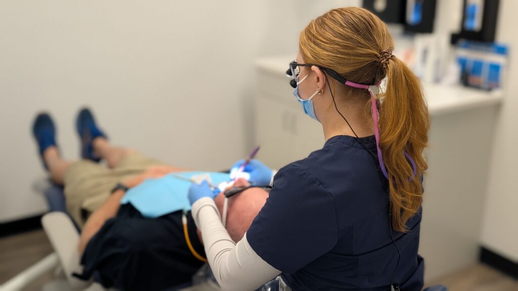 Dental professional treating a patient while wearing magnification loupes