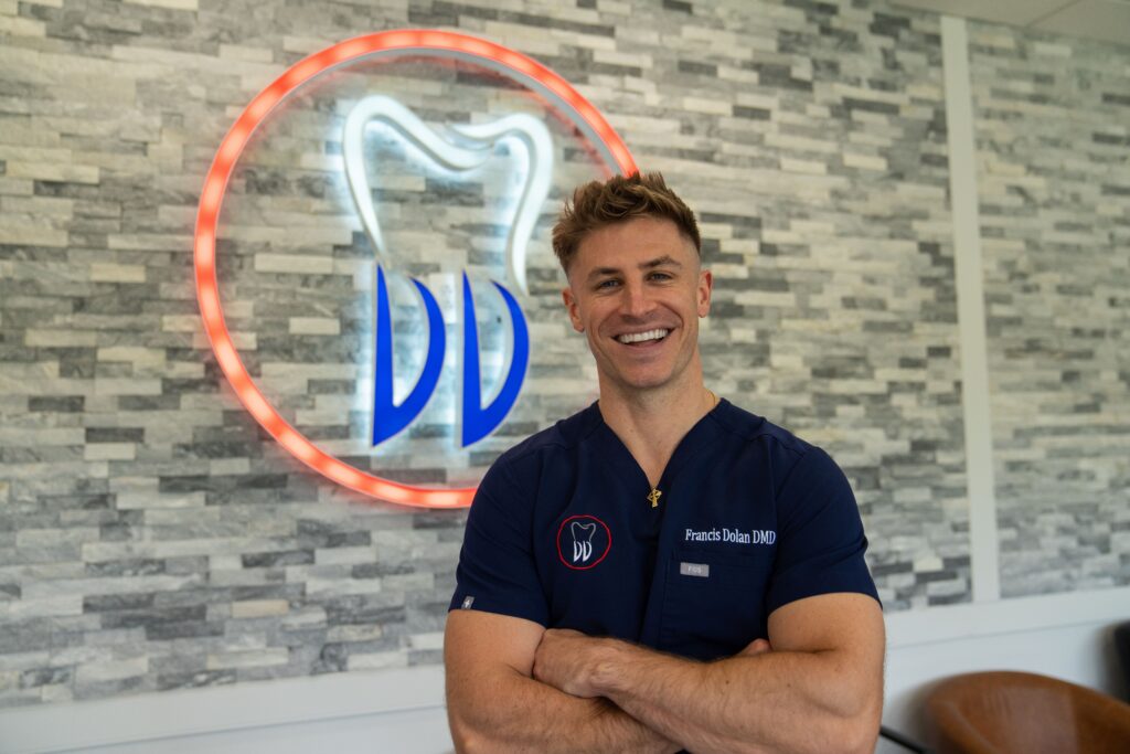 Dolan Dental dentist smiling beside practice branding