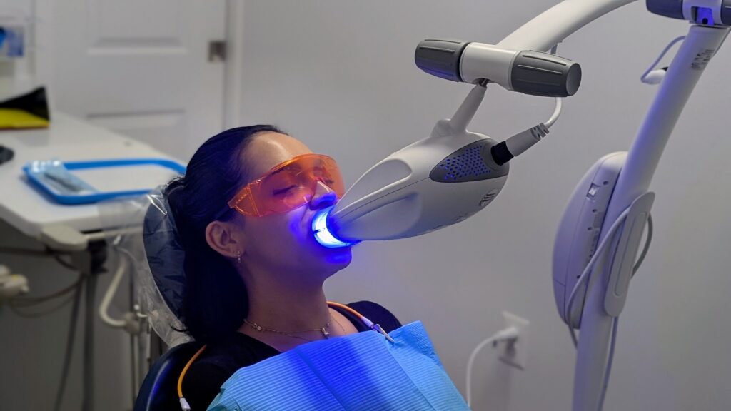 Patient receiving blue-light teeth whitening with protective glasses