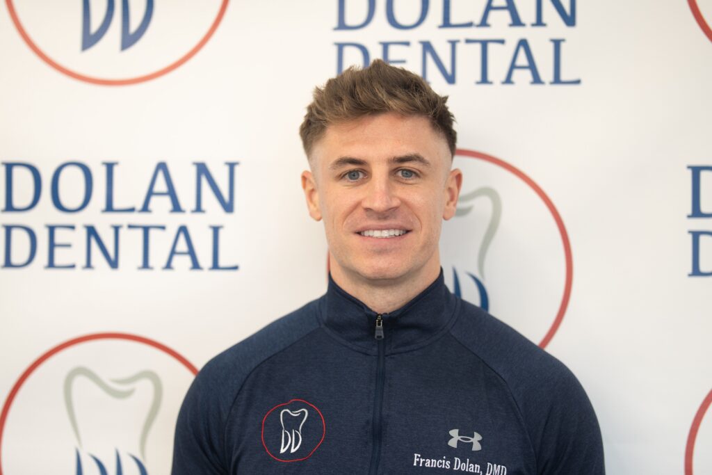 Dr. Francis Dolan smiling in front of Dolan Dental branding